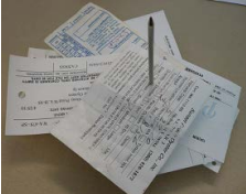 A silver pen is impaled through a stack of white paper forms.